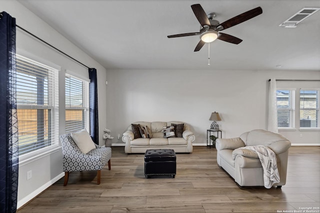 living area featuring a ceiling fan, baseboards, visible vents, and wood finished floors