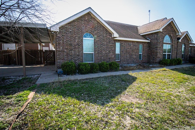 view of front of house with brick siding, a front lawn, and fence