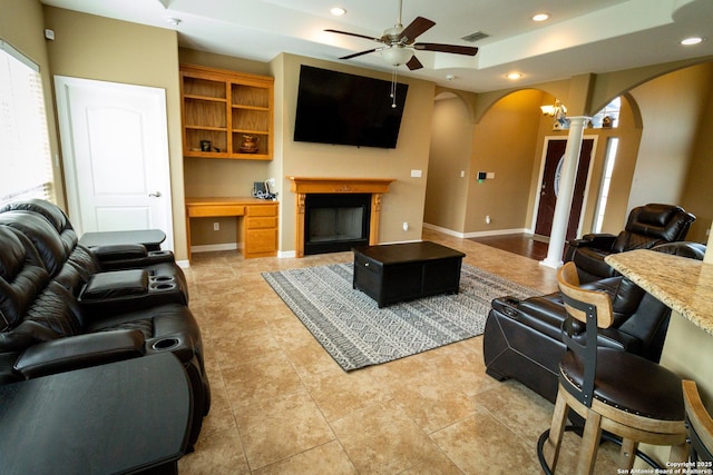 living room featuring arched walkways, recessed lighting, visible vents, built in study area, and a raised ceiling