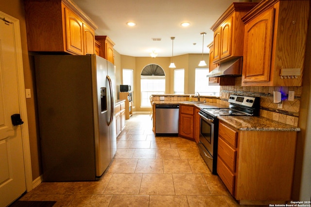 kitchen featuring under cabinet range hood, stainless steel appliances, a sink, decorative backsplash, and brown cabinetry