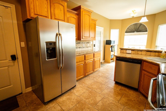 kitchen with light tile patterned floors, appliances with stainless steel finishes, plenty of natural light, and decorative backsplash