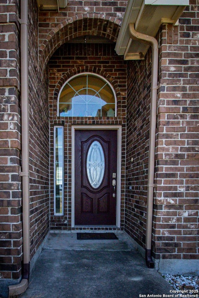 view of exterior entry with brick siding