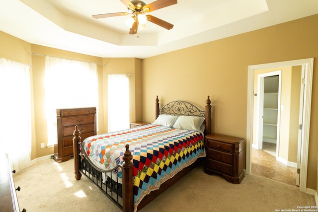 bedroom featuring ceiling fan, baseboards, a raised ceiling, and light colored carpet