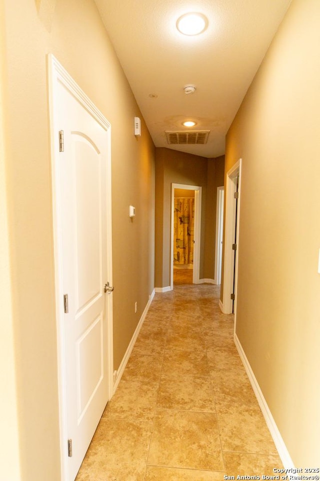 hallway featuring baseboards and visible vents