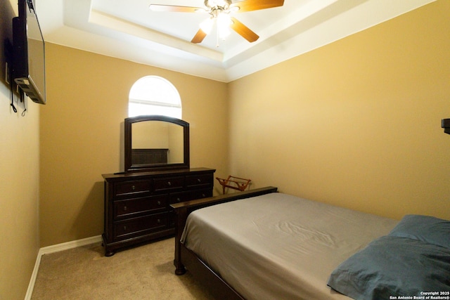 bedroom featuring baseboards, ceiling fan, a tray ceiling, and light colored carpet