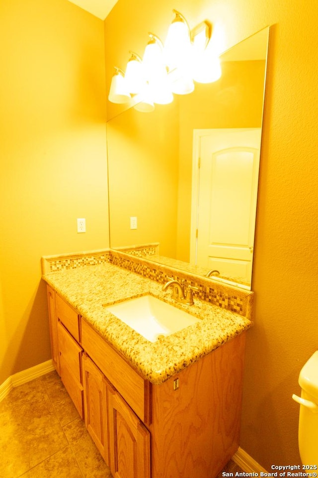 half bath featuring toilet, baseboards, a notable chandelier, and vanity