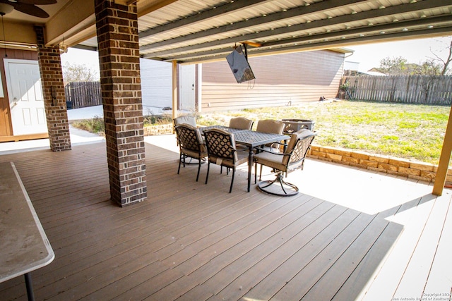 wooden terrace with outdoor dining area, fence, and ceiling fan