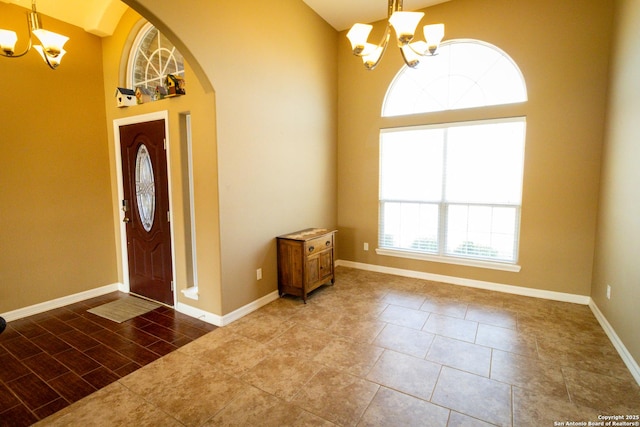 entryway with a towering ceiling, a chandelier, and arched walkways