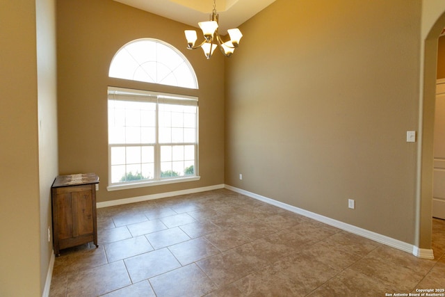 empty room featuring a notable chandelier, baseboards, and tile patterned floors