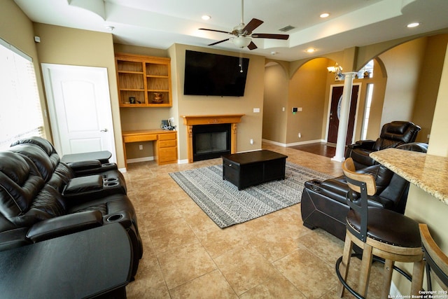 living room featuring visible vents, arched walkways, a raised ceiling, built in study area, and recessed lighting