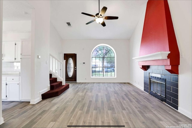 foyer featuring light wood-type flooring, stairway, visible vents, and a tiled fireplace