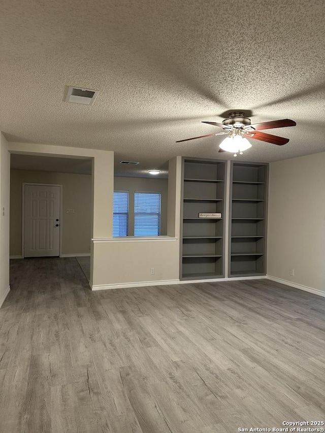 spare room featuring baseboards, visible vents, ceiling fan, wood finished floors, and a textured ceiling