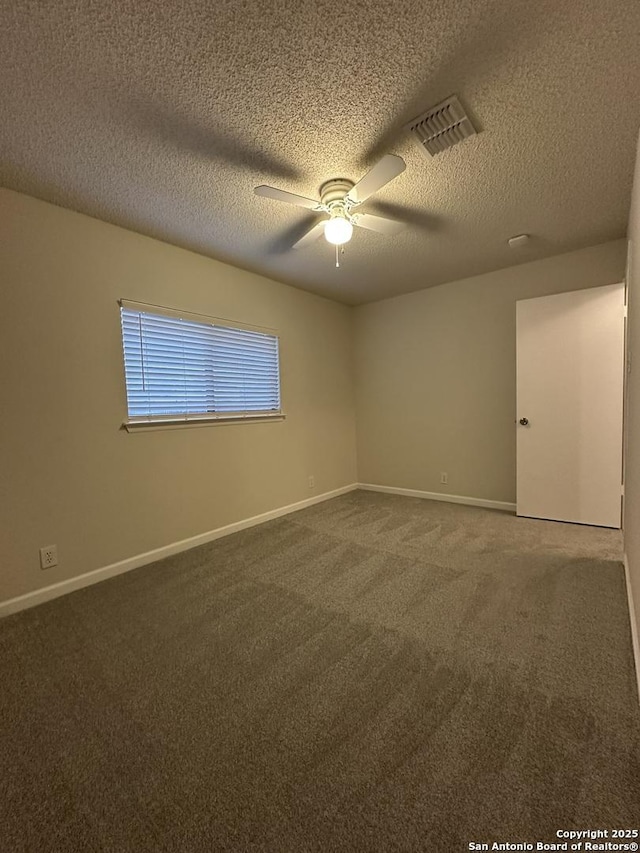 carpeted empty room featuring ceiling fan, a textured ceiling, visible vents, and baseboards