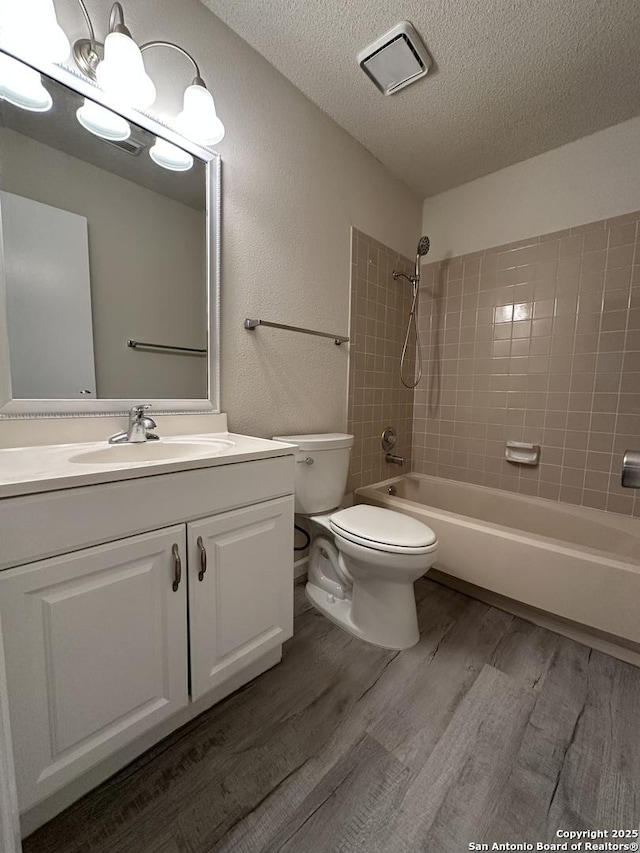 bathroom featuring a textured ceiling, toilet, wood finished floors, vanity, and washtub / shower combination