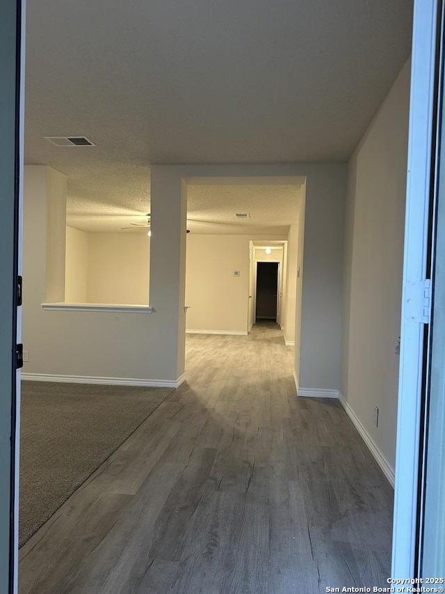 spare room featuring a textured ceiling, baseboards, and wood finished floors