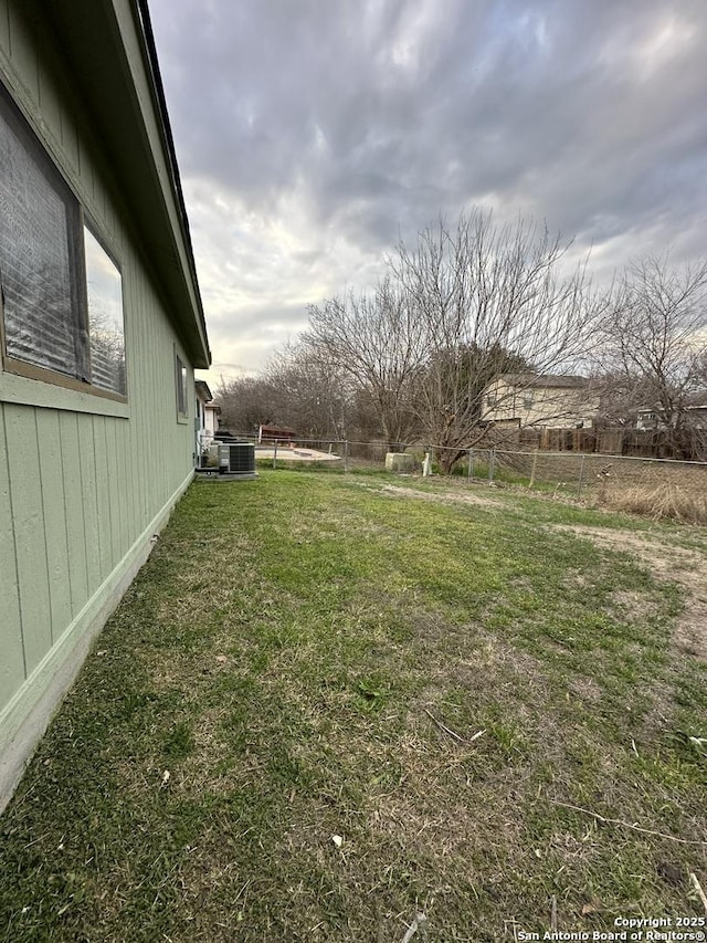 view of yard featuring central AC unit and fence