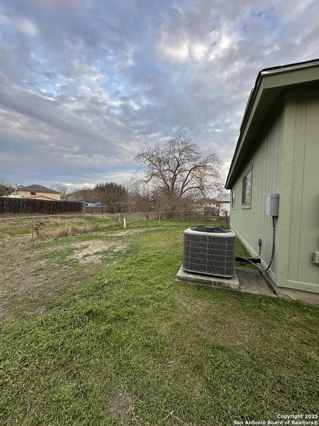 view of yard with central AC and fence