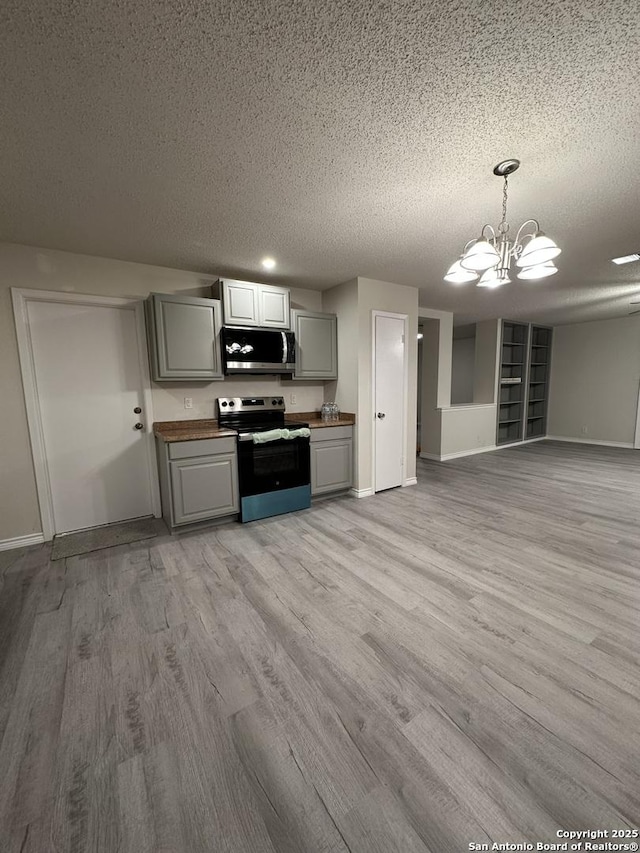 kitchen featuring stainless steel appliances, light wood finished floors, gray cabinetry, and a textured ceiling