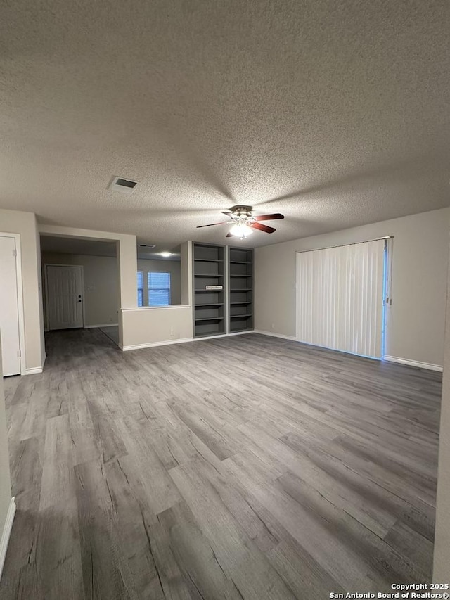 unfurnished living room with baseboards, wood finished floors, visible vents, and a ceiling fan