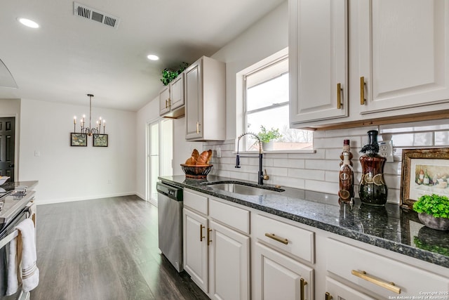 kitchen with visible vents, stainless steel appliances, decorative backsplash, a sink, and a notable chandelier
