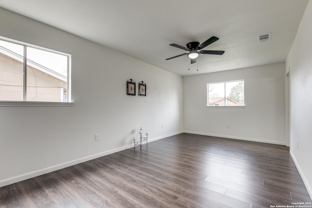 spare room with dark wood finished floors, baseboards, visible vents, and ceiling fan