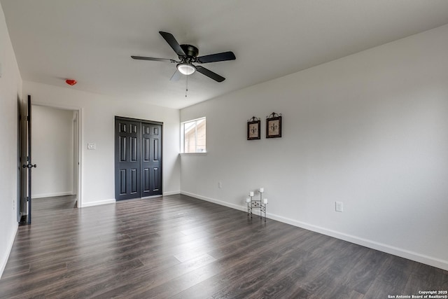 empty room featuring baseboards, a ceiling fan, and dark wood-style flooring
