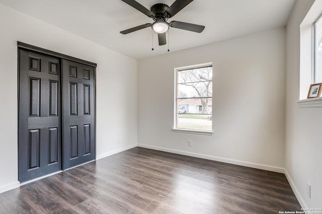 unfurnished bedroom with dark wood finished floors, ceiling fan, a closet, and baseboards