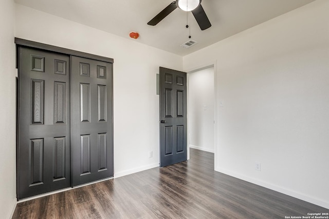 unfurnished bedroom with visible vents, dark wood-style floors, a closet, baseboards, and ceiling fan