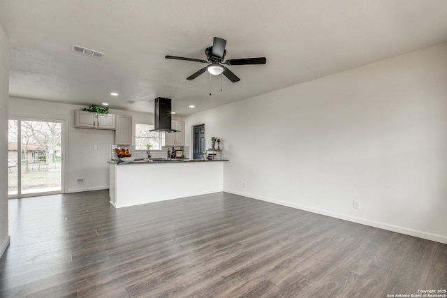 unfurnished living room featuring visible vents, baseboards, ceiling fan, and dark wood-style flooring