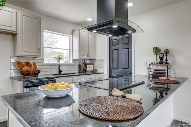 kitchen featuring baseboards, island exhaust hood, a sink, dishwasher, and backsplash
