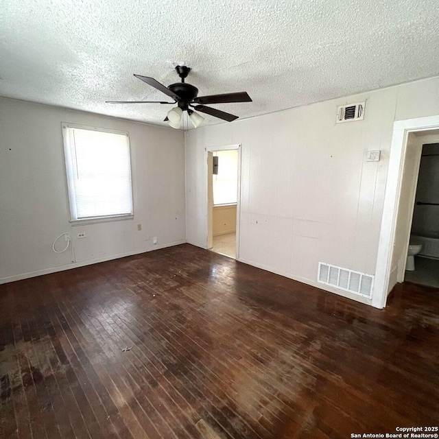 empty room with a ceiling fan, visible vents, a textured ceiling, and hardwood / wood-style floors