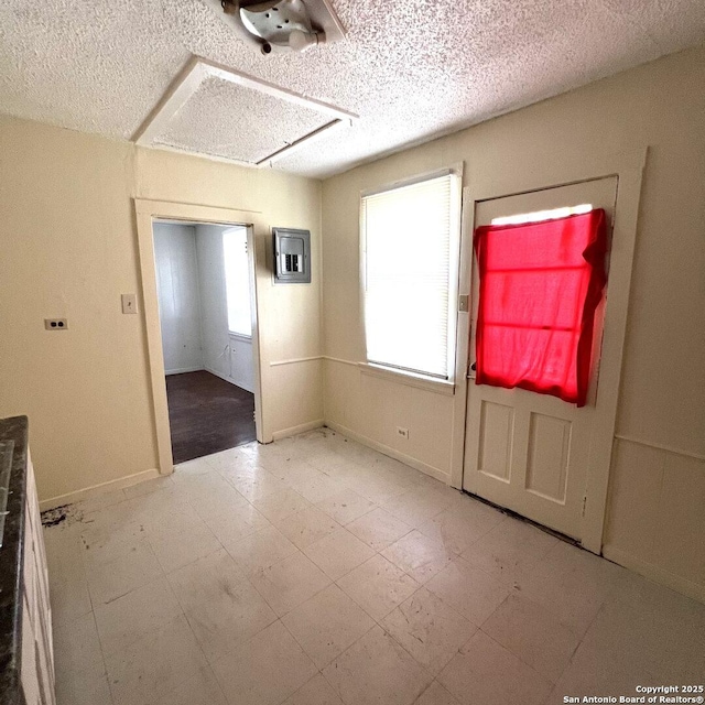 spare room featuring a healthy amount of sunlight, a textured ceiling, and light floors