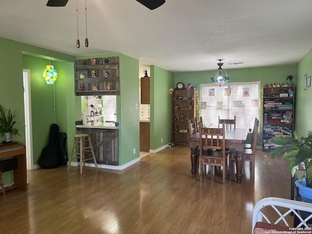 dining room featuring a ceiling fan, wood finished floors, visible vents, and baseboards