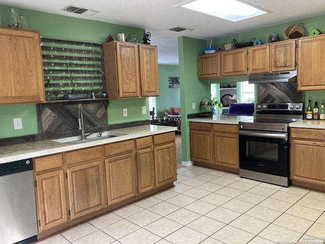 kitchen with under cabinet range hood, stainless steel appliances, a sink, visible vents, and light countertops