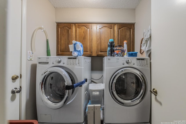 washroom with cabinet space, a textured ceiling, and washing machine and clothes dryer