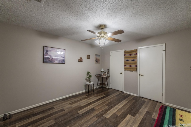 spare room featuring a textured ceiling, wood finished floors, a ceiling fan, and baseboards