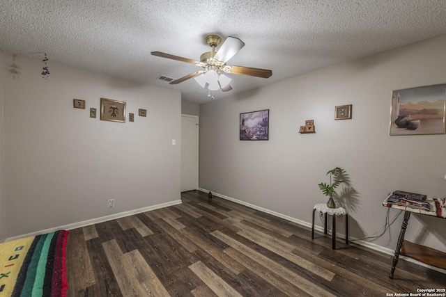 unfurnished room with ceiling fan, dark wood-style flooring, a textured ceiling, and baseboards