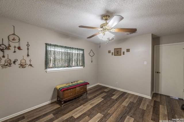 empty room with a textured ceiling, wood finished floors, visible vents, and baseboards