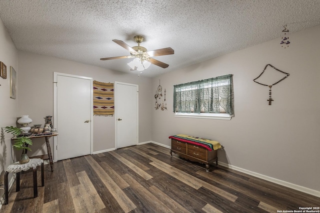 interior space featuring a textured ceiling, wood finished floors, a ceiling fan, and baseboards