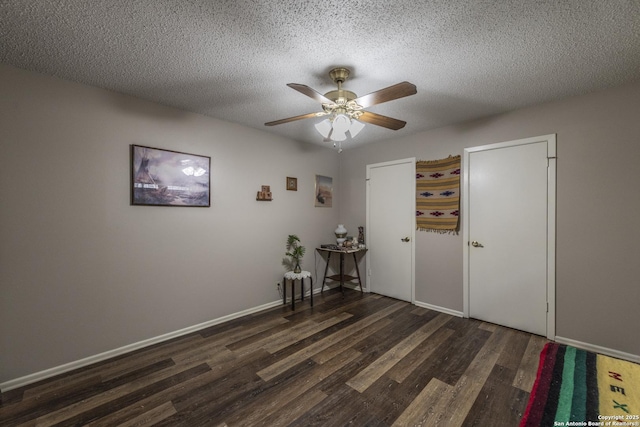 interior space with ceiling fan, a textured ceiling, baseboards, and wood finished floors