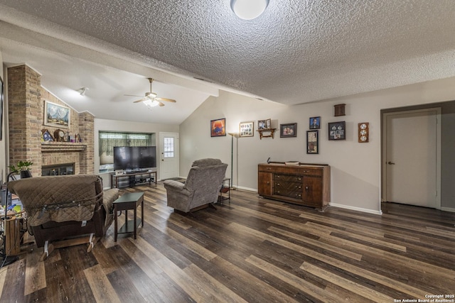 living room with vaulted ceiling, dark wood-style flooring, a fireplace, and a textured ceiling