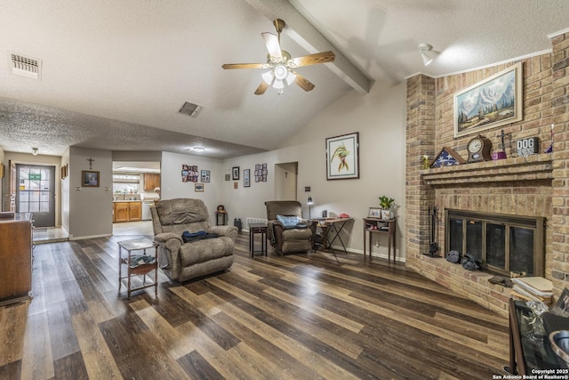 living area featuring a brick fireplace, a textured ceiling, visible vents, and beam ceiling