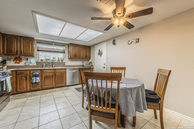 kitchen with light tile patterned floors, a sink, baseboards, appliances with stainless steel finishes, and brown cabinets