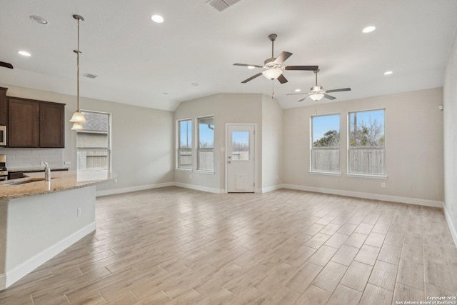 unfurnished living room featuring visible vents, a sink, light wood-style flooring, and baseboards