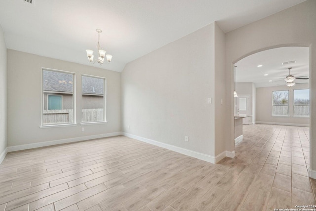 empty room with ceiling fan with notable chandelier, baseboards, arched walkways, and light wood-style floors