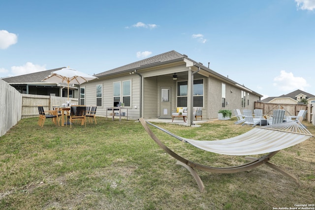 rear view of property featuring a patio, a lawn, a fenced backyard, and a ceiling fan