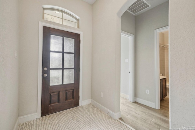 entrance foyer featuring baseboards, plenty of natural light, visible vents, and light wood-style floors