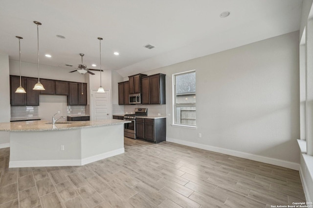 kitchen with dark brown cabinetry, stainless steel appliances, a sink, visible vents, and tasteful backsplash