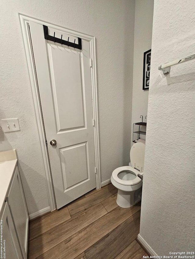 106 Tokalaun Dr, Hutto, TX 78634 - bathroom with a textured wall, toilet, vanity, wood finished floors, and baseboards