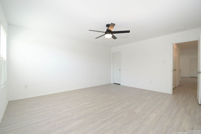 spare room featuring ceiling fan, light wood-style flooring, and baseboards